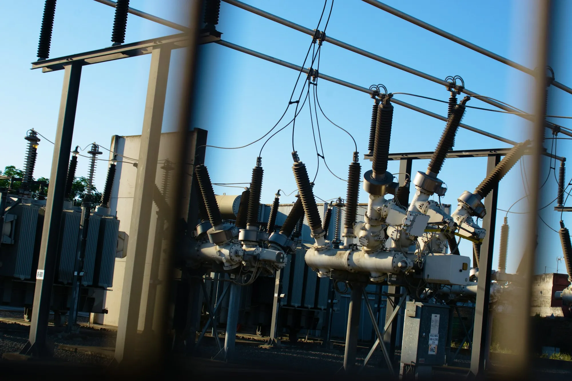 High-voltage substation seen through its perimeter fence